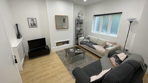 En moderne stue med sofa, sofabord og fjernsyn.