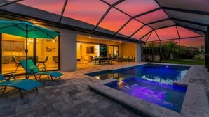 A covered outdoor area with a pool, lounge chairs, and a dining area.