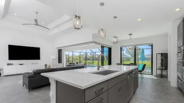 A modern kitchen with a large island, a flat-screen TV, and a view of the outdoors.
