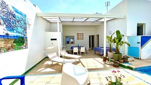A sunlit patio with lounge chairs, a dining table, and a pool area. - Casa Mondrian - Camere con Bagno e Piscina Privata (Tiggiano)