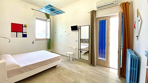 A bedroom with a bed, a chair, a mirror, a window, and an air conditioning unit. - Casa Mondrian - Camere con Bagno e Piscina Privata (Tiggiano)