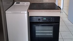 A compact kitchen with a built-in oven, a microwave, and a stainless steel range hood. - Beautiful bright apartment on the seafront (Port-la-Nouvelle)