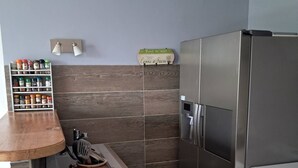 A kitchen with a stainless steel refrigerator, a spice rack, a wooden countertop, and a tiled backsplash. - Beautiful bright apartment on the seafront (Port-la-Nouvelle)