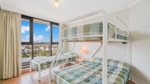 Une chambre de dortoir avec des lits superposés, une fenêtre avec des rideaux et une vue sur la ville.