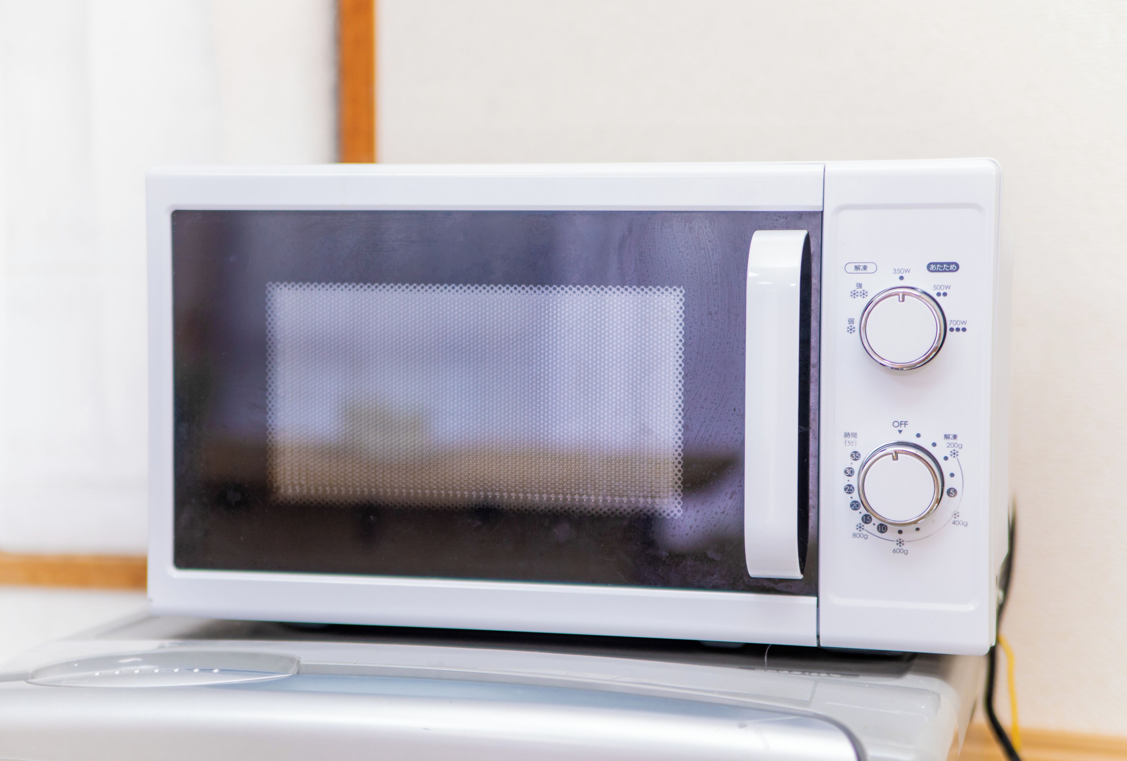 A white microwave with a digital display and two control knobs.