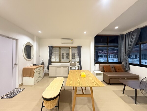 Una sala de estar moderna con una mesa de madera, un banco, un sofá y una ventana con cortinas.