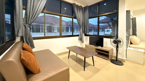 A modern living room with a sofa, a coffee table, a TV, and a fan. - Relaxing Escape in Hua Hin City 94/2 (Tambon Hua Hin)