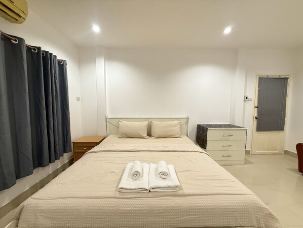 A hotel room with a bed, a nightstand, a dresser, and a door.