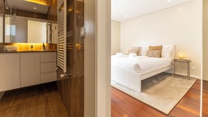 Une chambre moderne avec un grand lit, une table de chevet et une petite table de nuit avec une lampe.