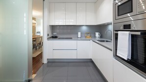 Une cuisine moderne avec des meubles blancs, des appareils en acier inoxydable et un plan de travail gris.