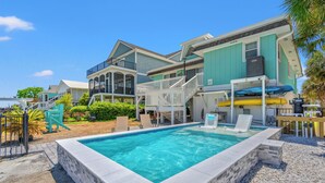 A swimming pool surrounded by a two-story house with a balcony and a covered patio area. - Channeling The Sun-4BR/2BA Channel House- Pets (North Myrtle Beach)
