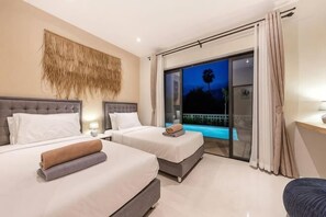 Habitación de hotel con dos camas, un balcón con piscina y vistas al cielo nocturno.