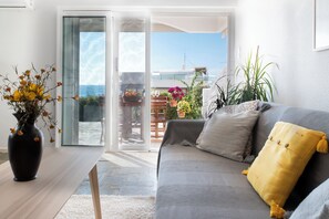 A modern living room with a grey sofa, a yellow pillow, and a vase with flowers on a table. - Panoramic Seaview Maisonette with Garden steps from the beach (Saronida)