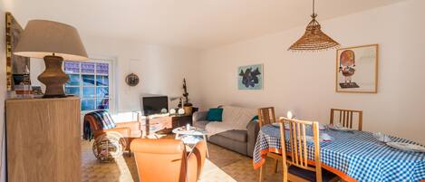 A living room with a sofa, coffee table, and dining table set with a checkered tablecloth.