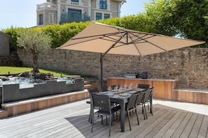 Un patio al aire libre con una mesa lista para comer, un muro de piedra y un jacuzzi.