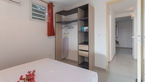 A bedroom with a bed, a wardrobe, a radiator, and a window with curtains.
