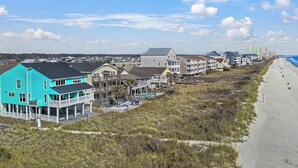 A coastal residential area with houses along the beach, featuring a prominent turquoise building with a balcony. - Twin Palms Beach House (Sleeps up to 26) (North Myrtle Beach)