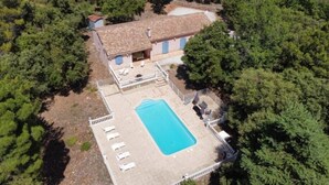 Vista aérea de una casa con piscina, rodeada de árboles.