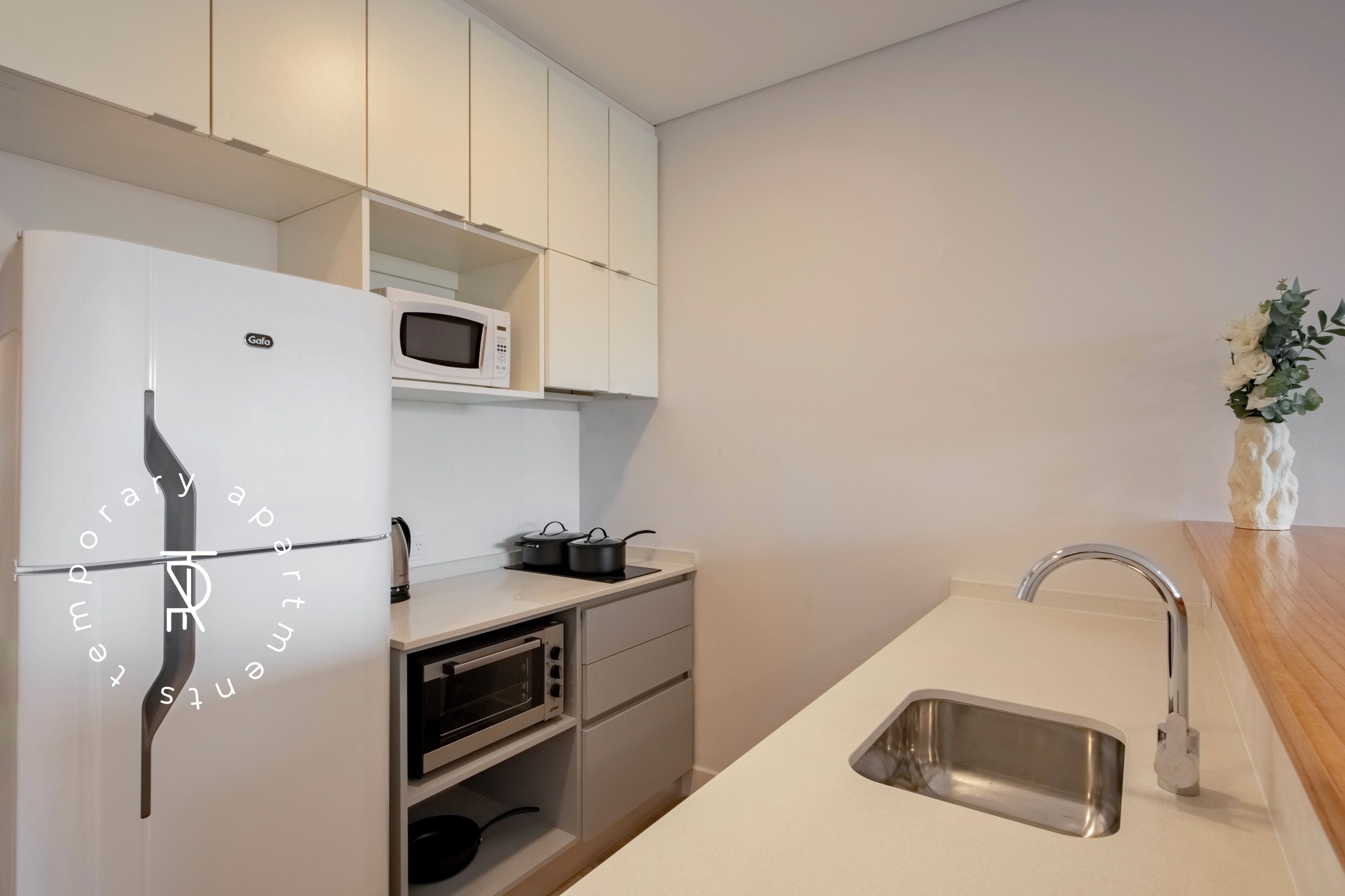A modern kitchen with a built-in refrigerator, microwave, oven, and sink.