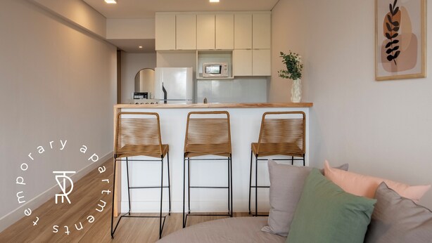 A modern kitchen with white cabinets, a microwave, and a small island with bar stools. - Top Rentals Palermo Soho (Buenos Aires)