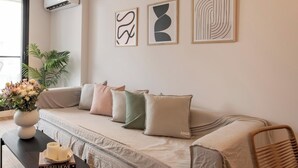 A modern living room with a sofa, cushions, a vase with flowers, a table with books and candles, and abstract wall art. - Top Rentals Palermo Soho (Buenos Aires)