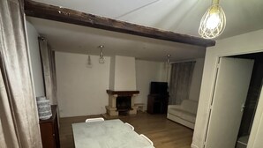 A dining area with a table and chairs, a fireplace, and a television. - Appartio - Large house near PARIS (Villiers-le-Bel)