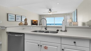 A modern kitchen with a double sink, white cabinets, and a ceiling fan.