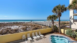 A pool area with lounge chairs and a view of the beach.