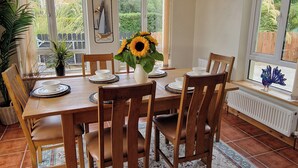 Ein Essbereich mit Holztisch, Stühlen und einer Vase mit Sonnenblumen.