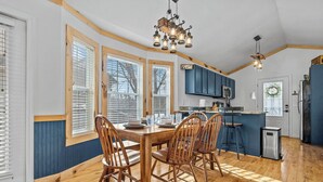 A kitchen with wooden cabinets, a dining table with chairs, and a chandelier. - BigFoot Inn, once you’ve seen it, you won’t want to leave! (PIGEON FORGE)
