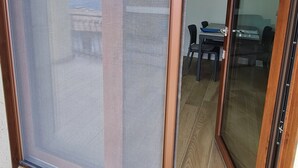 Una habitación con puerta corrediza de vidrio que da a un espacio exterior con mesa y sillas.