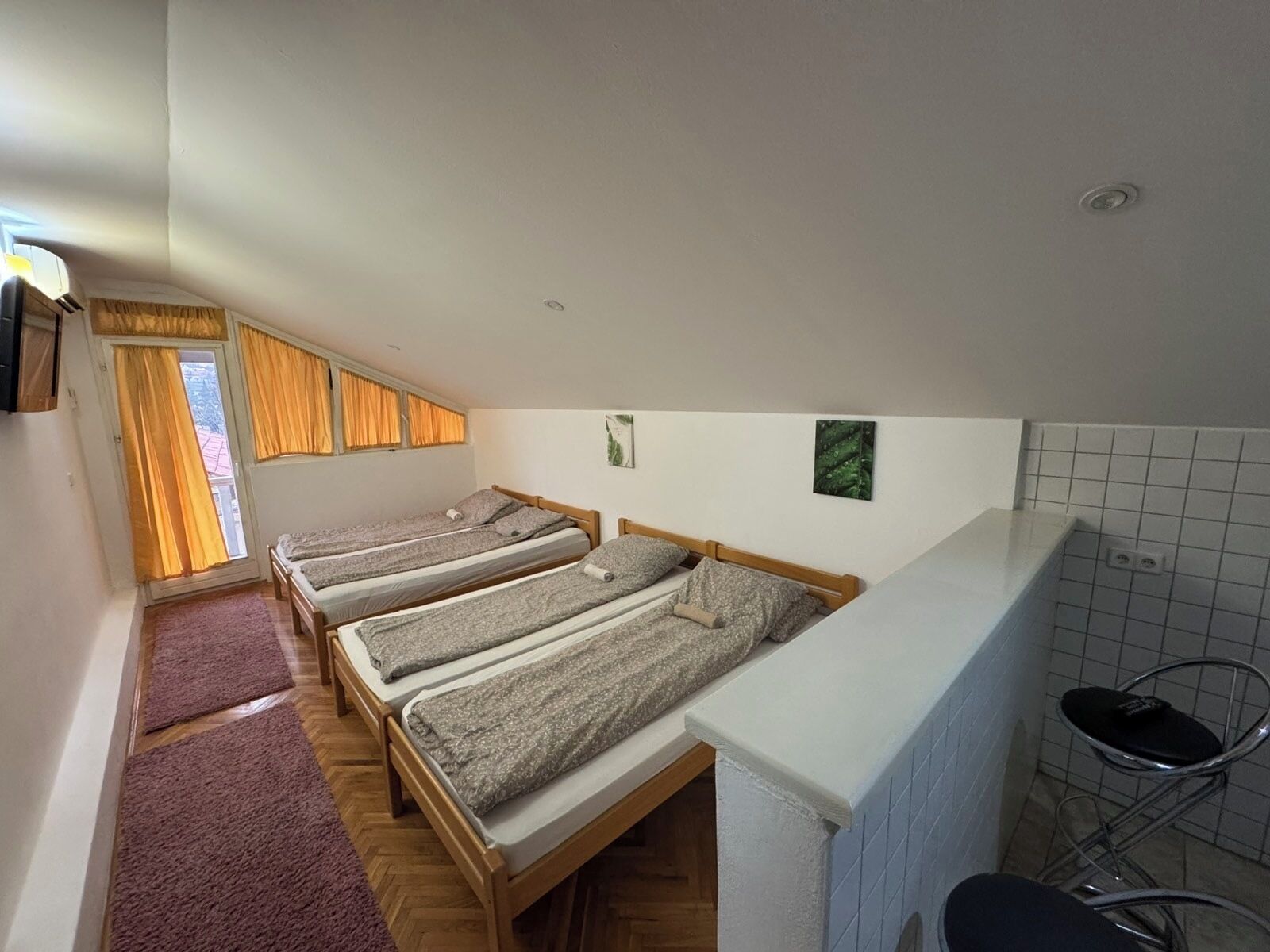A compact room with three single beds, a kitchenette, and a small bathroom.