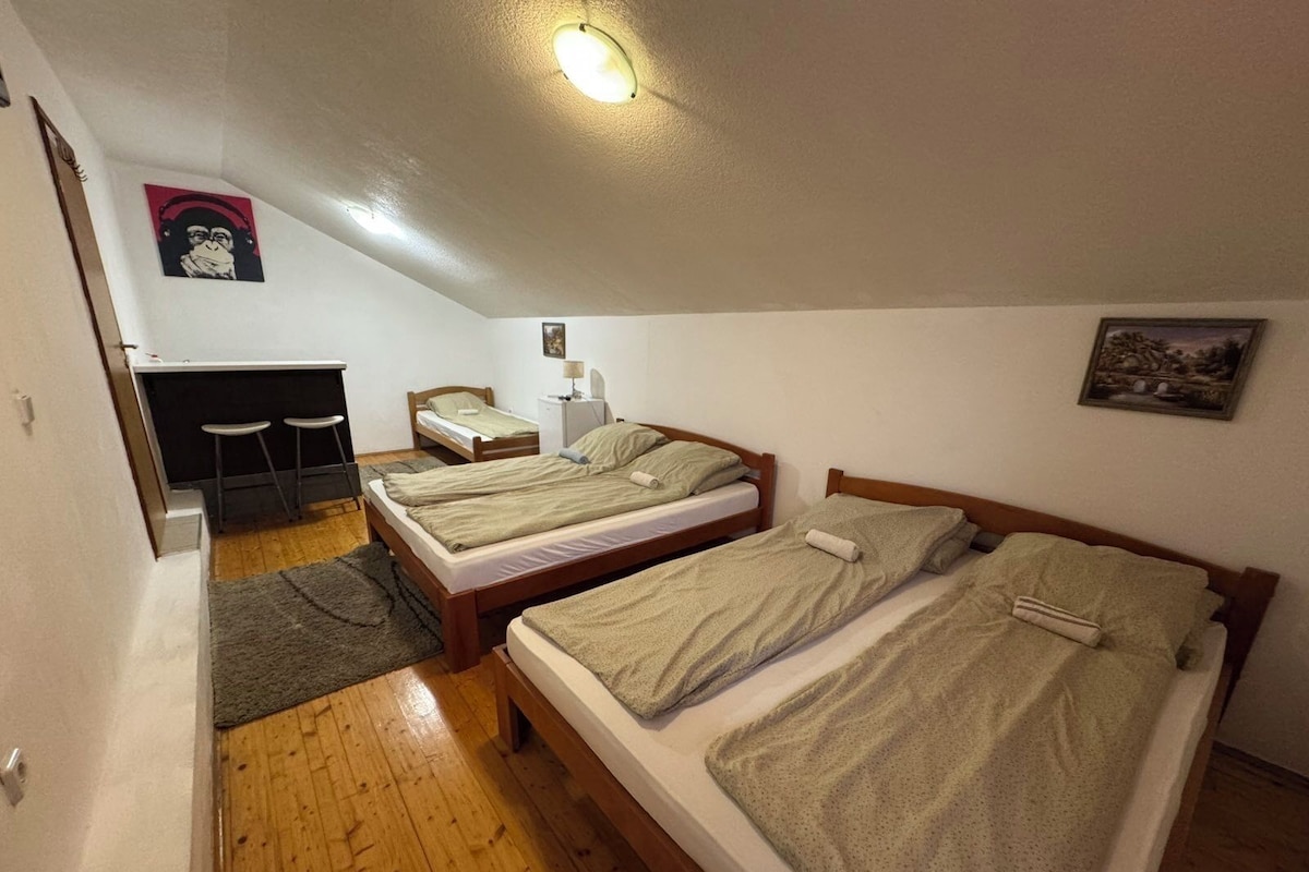 A small, cozy room with two wooden beds, a desk, and a chair.