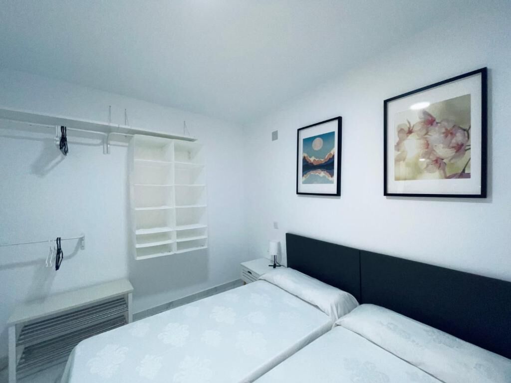 Ein Schlafzimmer mit zwei Betten, einem weißen Schrank und zwei gerahmten Bildern an der Wand.