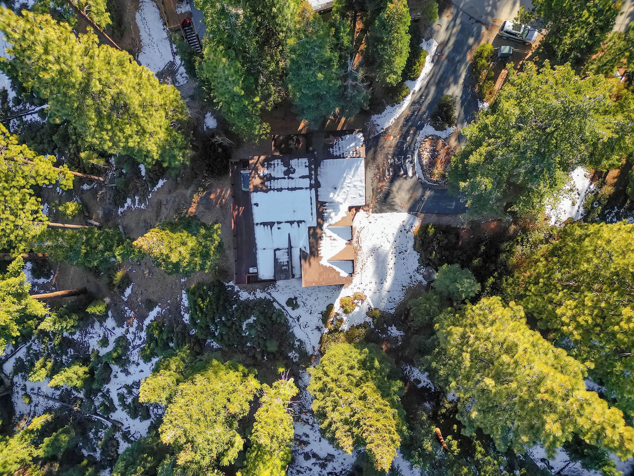 Vista aèria d'una casa envoltada d'arbres i amb petites zones de neu.