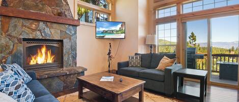 Una sala de estar acogedora con chimenea de piedra, televisor de pantalla plana, sofá y mesa de centro.