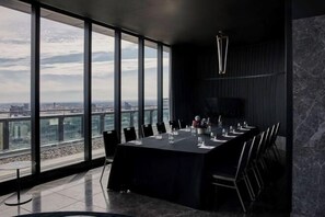 Une salle de conférence dotée d’une longue table, de chaises et offrant une vue sur la ville grâce à de grandes fenêtres.