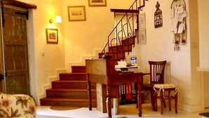 A cozy living room with a wooden staircase, a dining table, and a floral armchair.