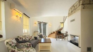 A living room with a sofa, coffee table, and a fireplace. There is a staircase leading to an upper level.
