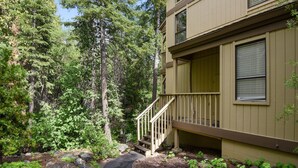 Un bâtiment à deux étages doté d’une terrasse en bois et d’un chemin en pierre menant à l’entrée.