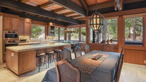 A spacious kitchen with a large island, wooden cabinetry, and a dining area with a long table and chairs.