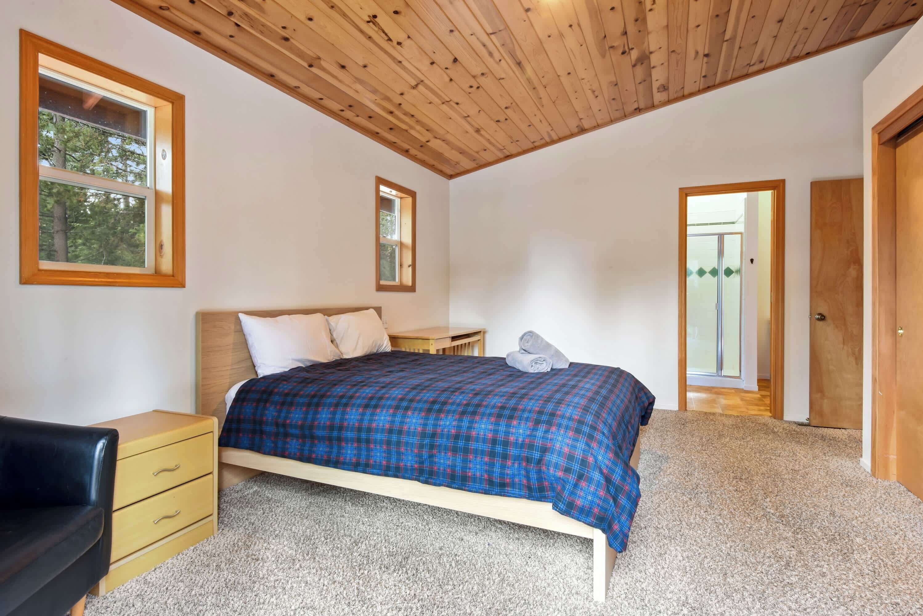 A bedroom with a bed, a nightstand, a dresser, and a door.