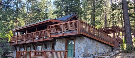 A two-story log cabin with a stone foundation, wooden balconies, and a stone entrance.
