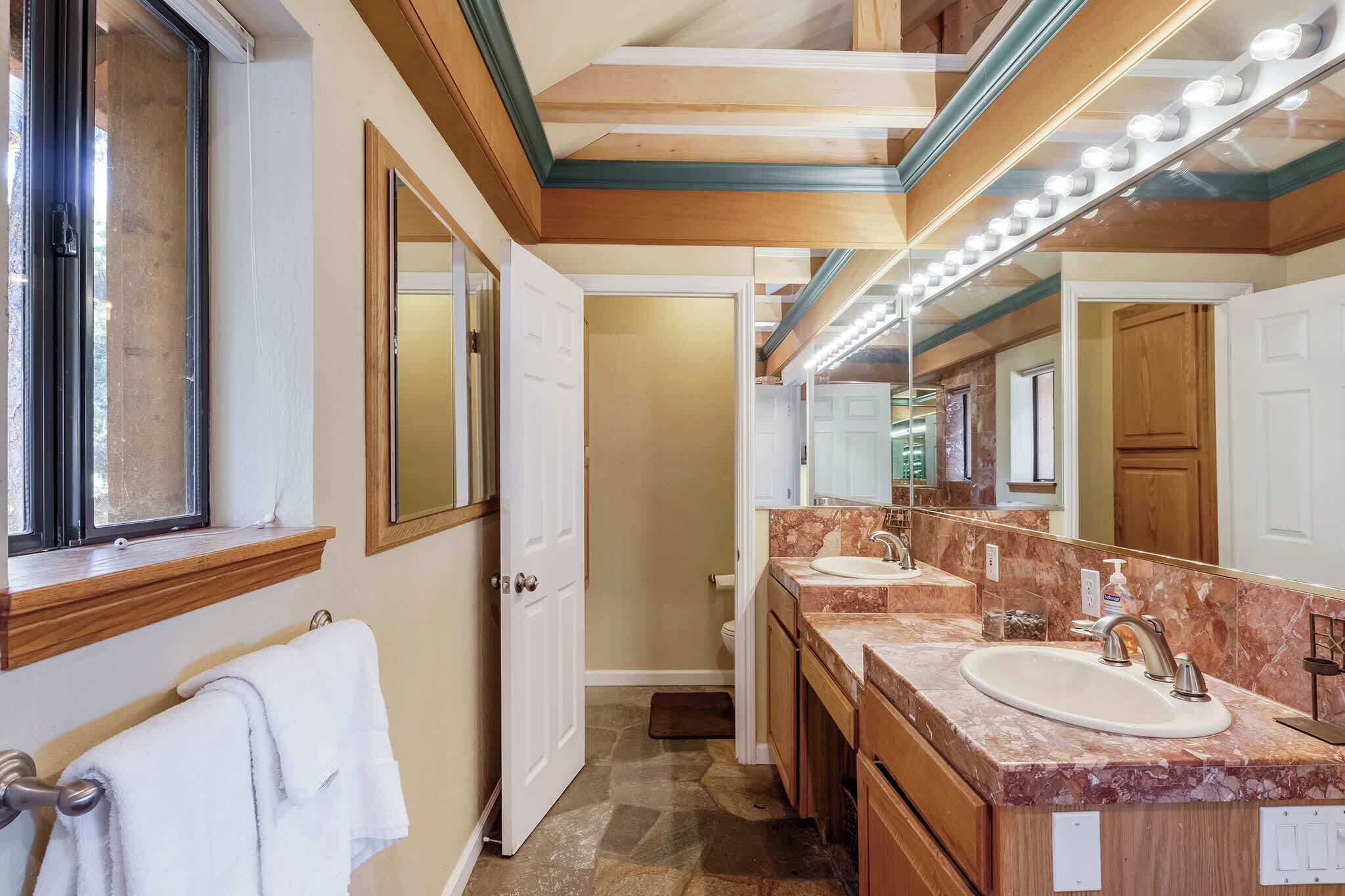 Un bagno con un lavabo, due lavandini, uno specchio grande e una finestra.