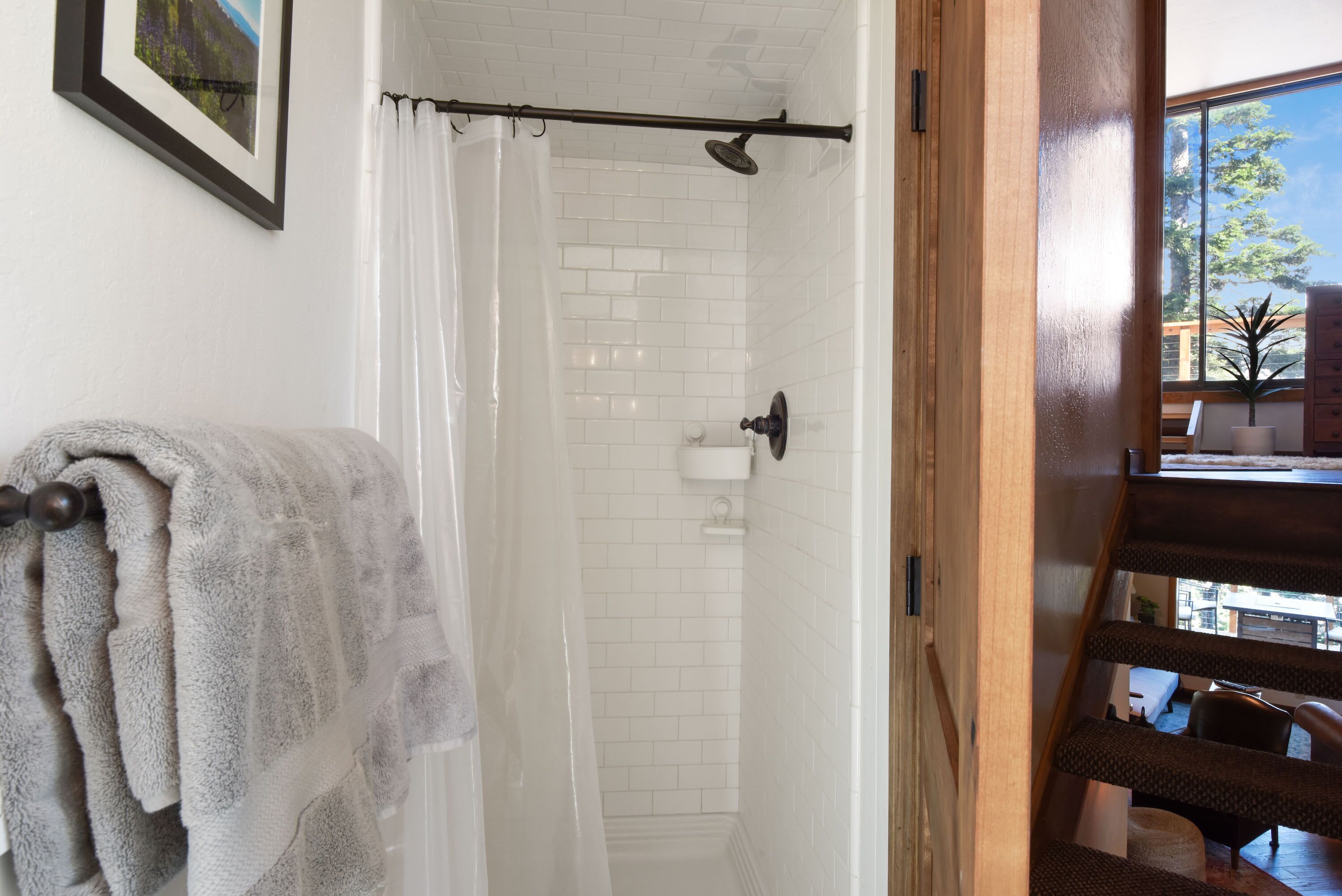 A bathroom with white tiled walls, a shower with a glass door, and a towel rack with a folded towel.