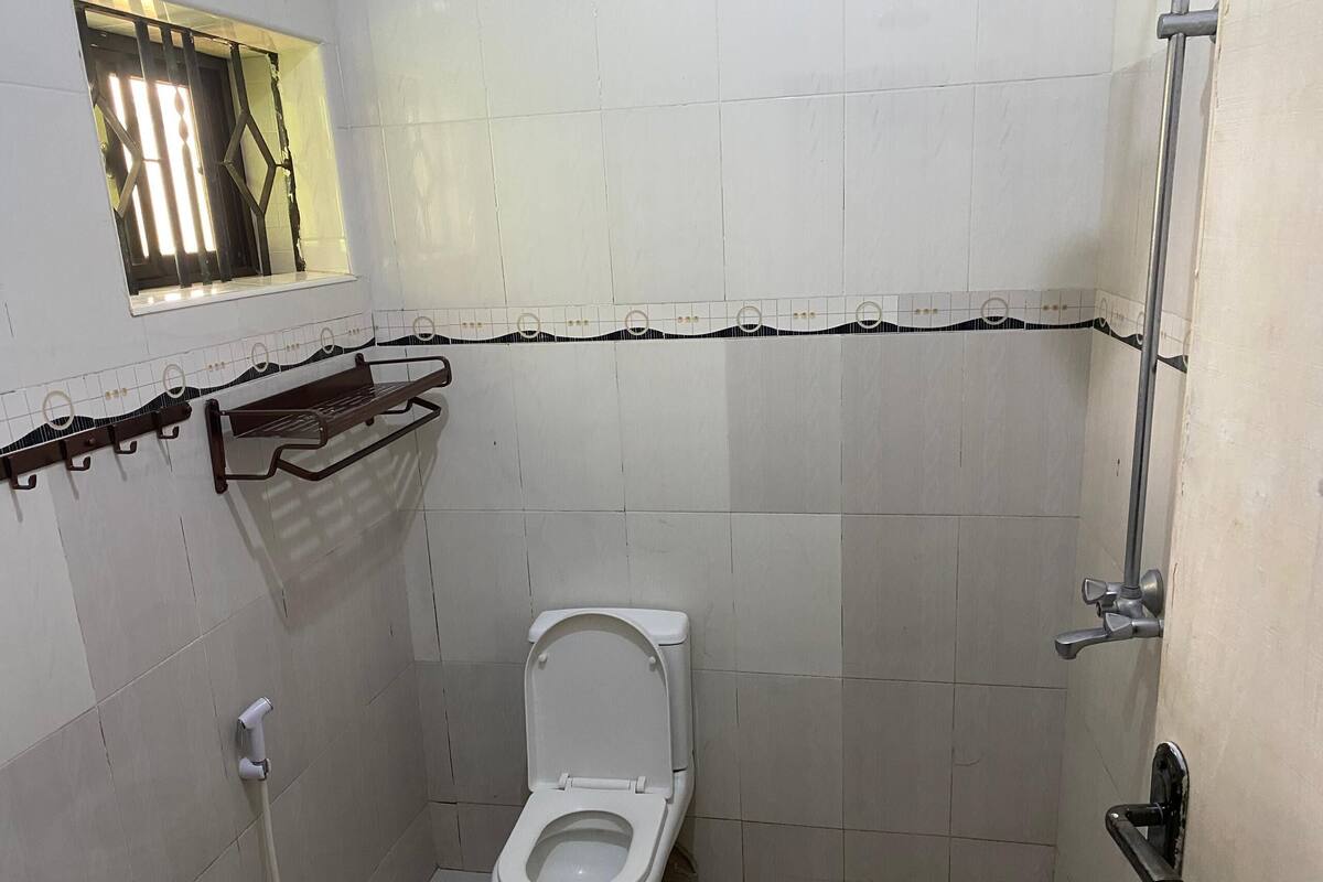 A small, tiled bathroom with a toilet, a shower, and a towel rack.