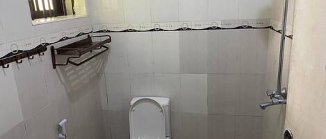 A small, tiled bathroom with a toilet, a shower, and a towel rack.