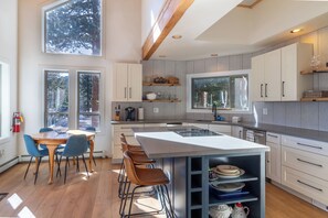 A modern kitchen with a central island, bar stools, and a dining area with a table and chairs.