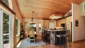 Eine geräumige Küche mit Holzausstattung, einer zentralen Kochinsel mit Barhocker und großen Fenstern für natürliches Licht.