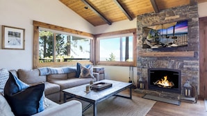Una sala de estar acogedora con chimenea de piedra, ventanas amplias, un sofá y una mesa de centro.